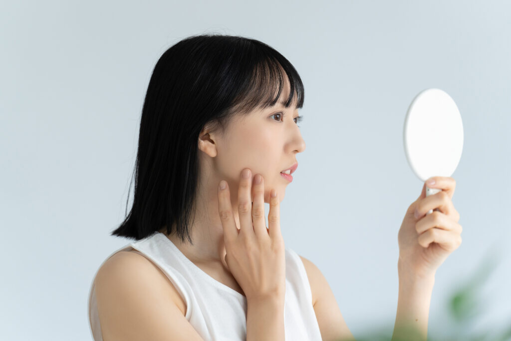 鏡を見て肌チェックをする女性